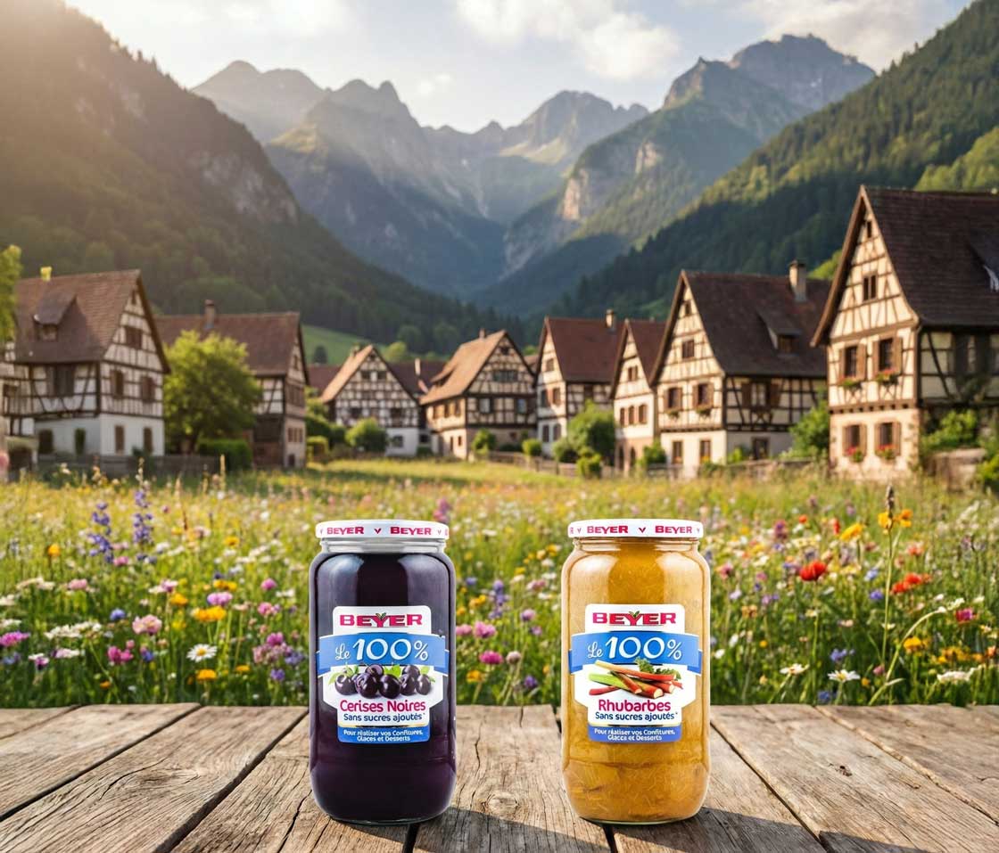 Un pot de pur�e 100% fruits Beyer, pos� dans la neige devant un chalet et un sapin de No�l qui brille.